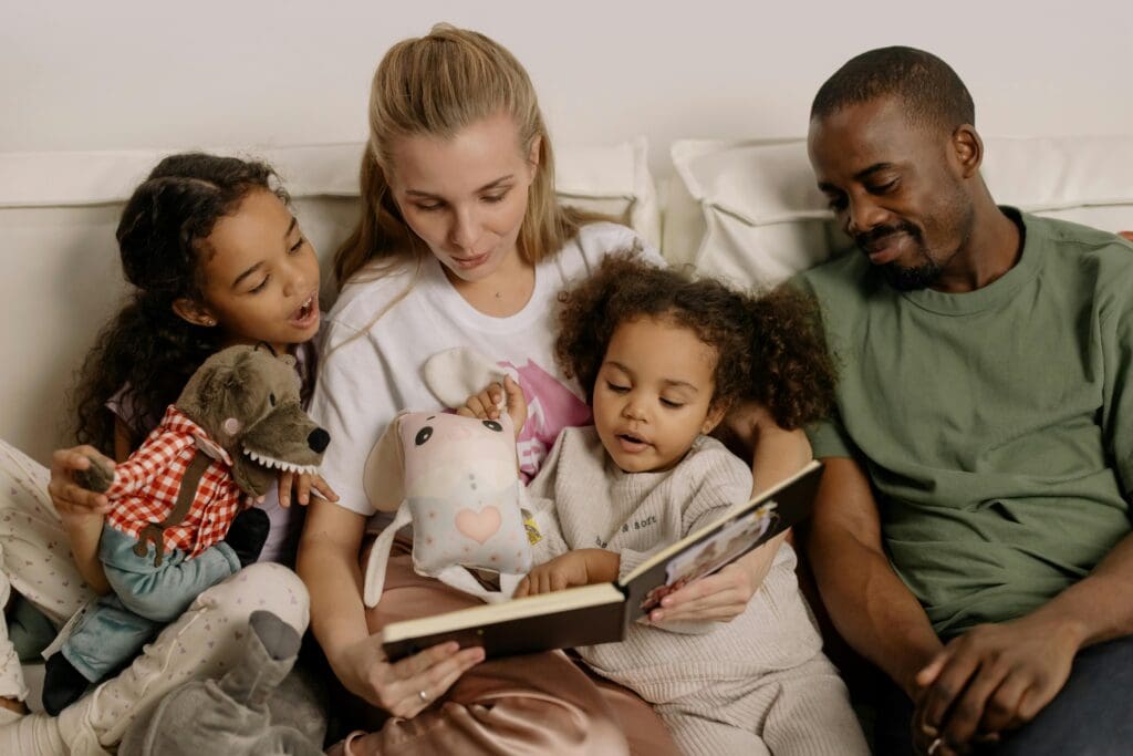 mother and faither with two young girls reading a book on a couch, foster parenting requirements