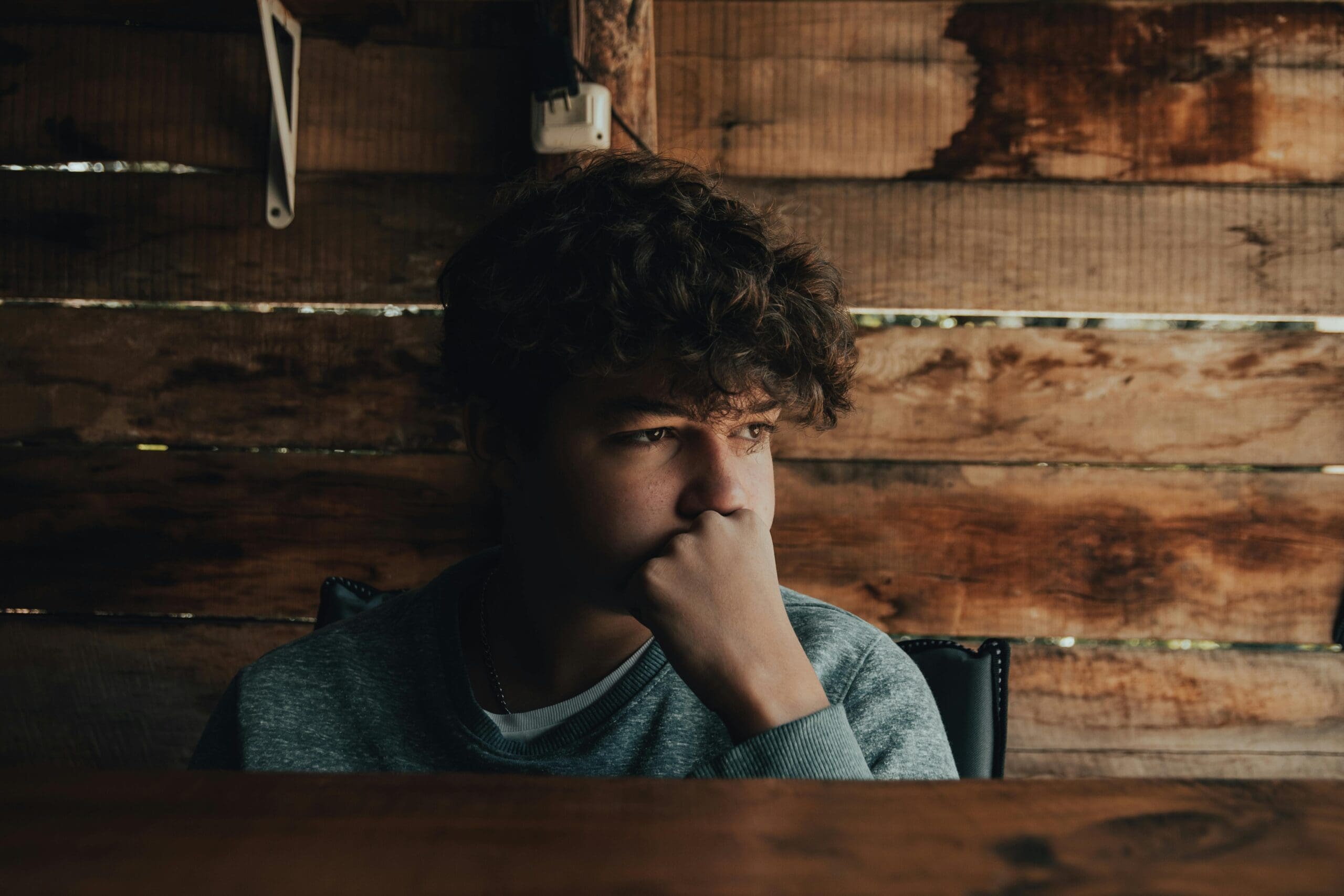 white teen sitting in a shed in deep thought
