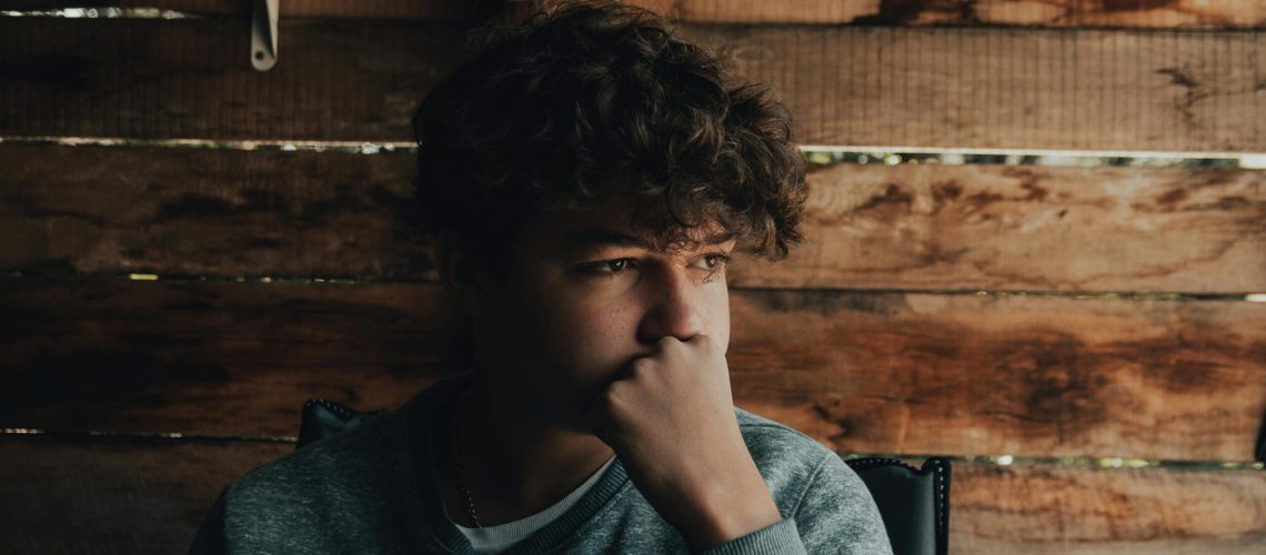 white teen sitting in a shed in deep thought